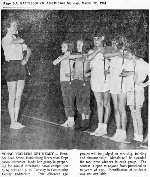 Children stand in line holding batons