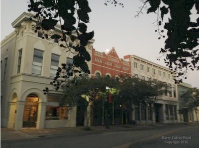 A downtown building with the moon setting in the distance