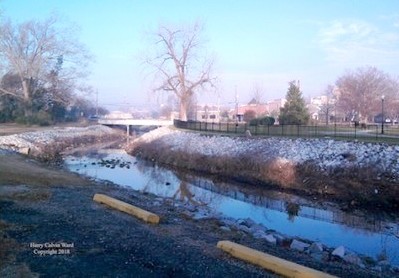 A creek in winter with no leaves on nearby trees